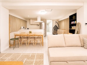 A modern living space with a dining area, kitchen, and a sofa.