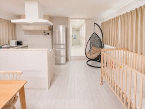 A modern kitchen with a built-in oven, a hanging chair, and a wooden crib.