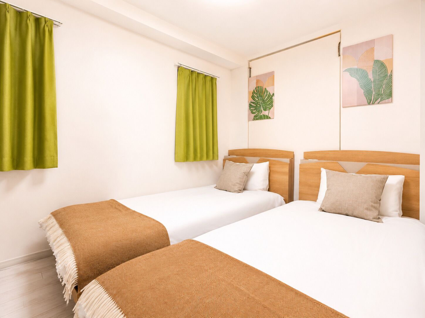 A hotel room with two beds, green curtains, and wall art.