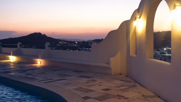 A rooftop pool area with a view of the city at dusk.