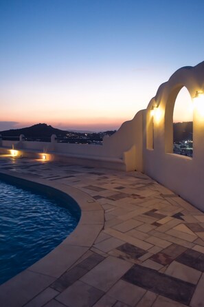A rooftop pool area with a view of the city at dusk. - Complex of Cycladic traditional houses (Mykonos)
