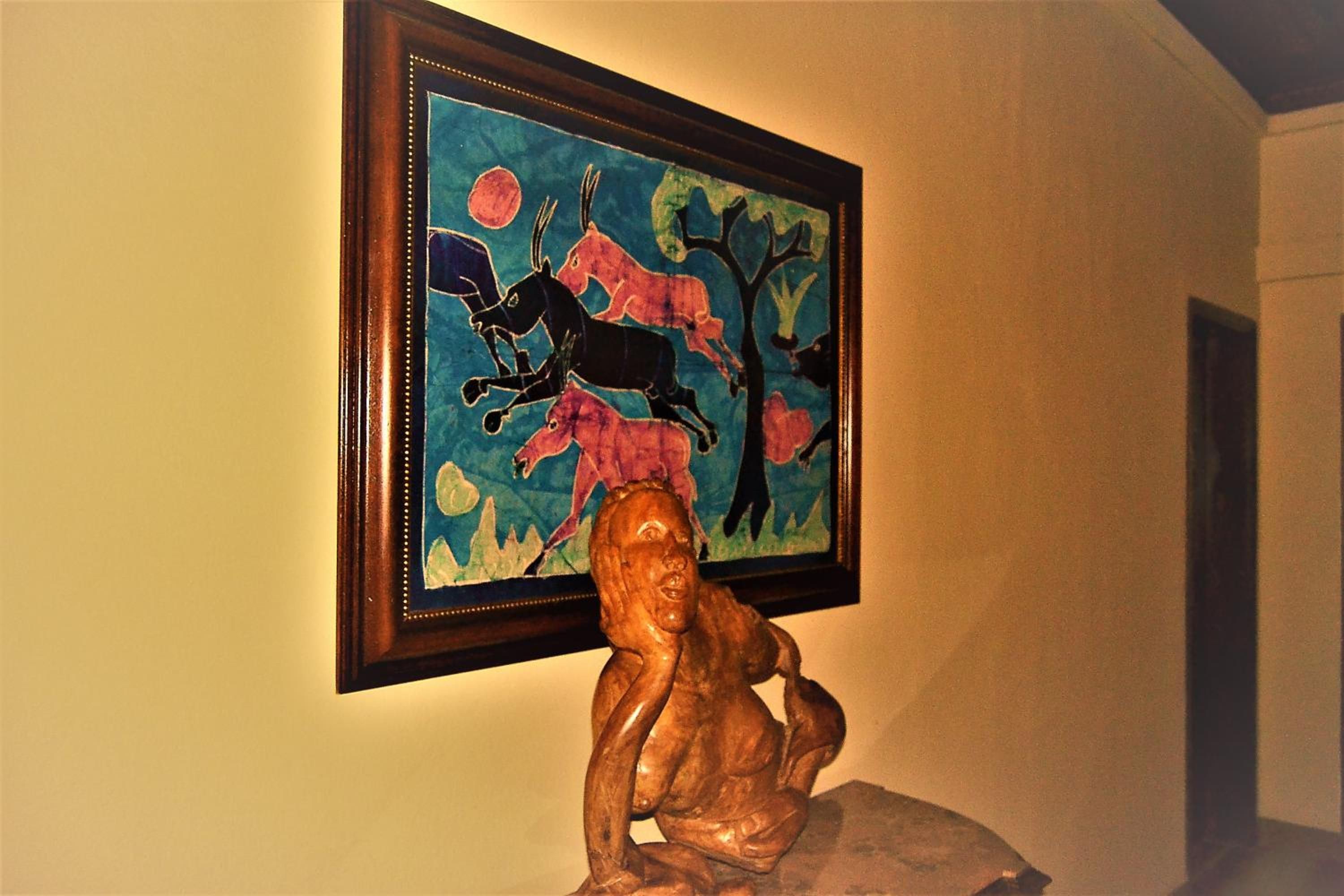 Une œuvre d’art encadrée, représentant des figures abstraites, et une sculpture en bois, le tout accroché à un mur.