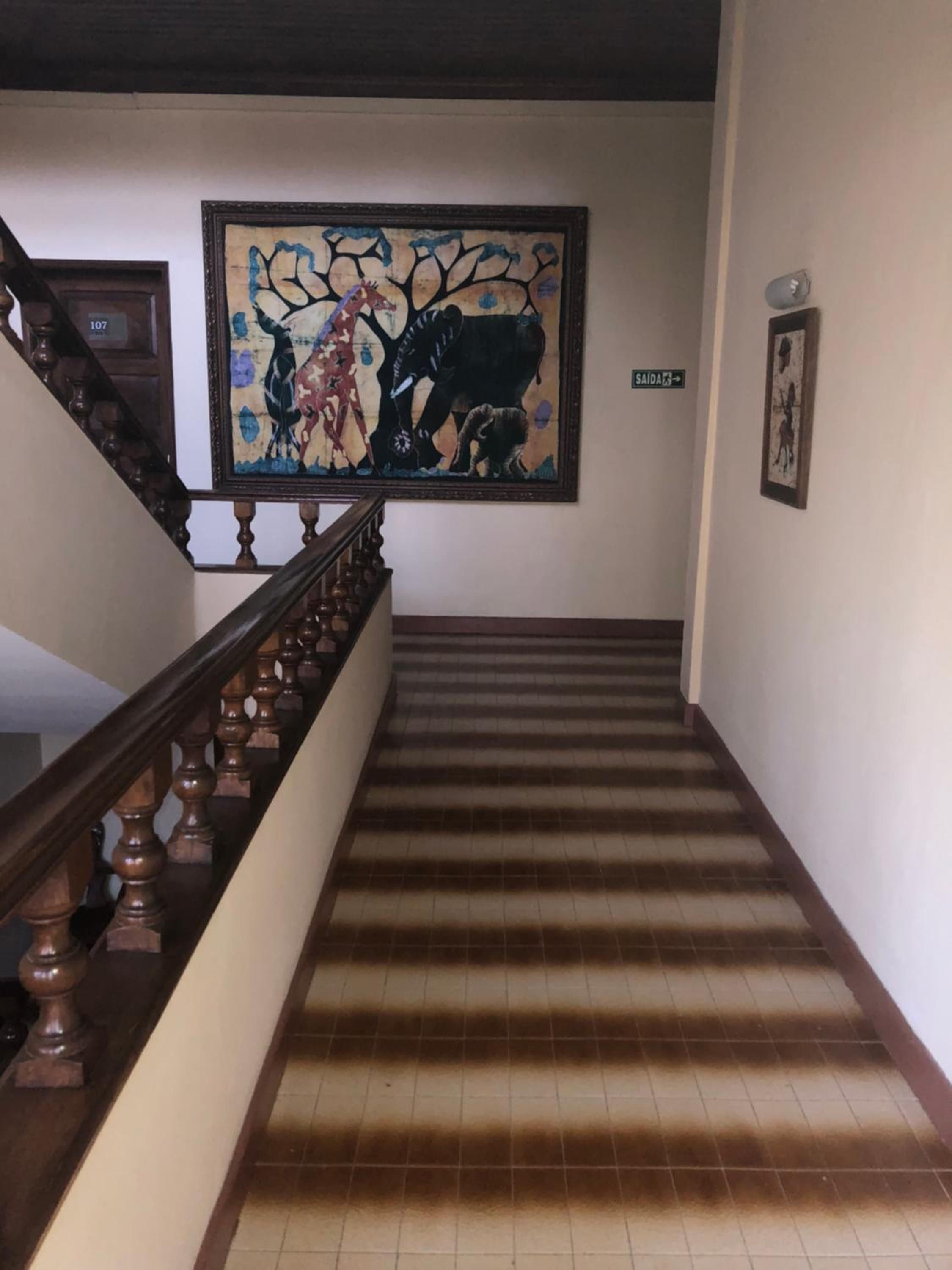 A staircase with a handrail and a tiled floor leading to a landing.