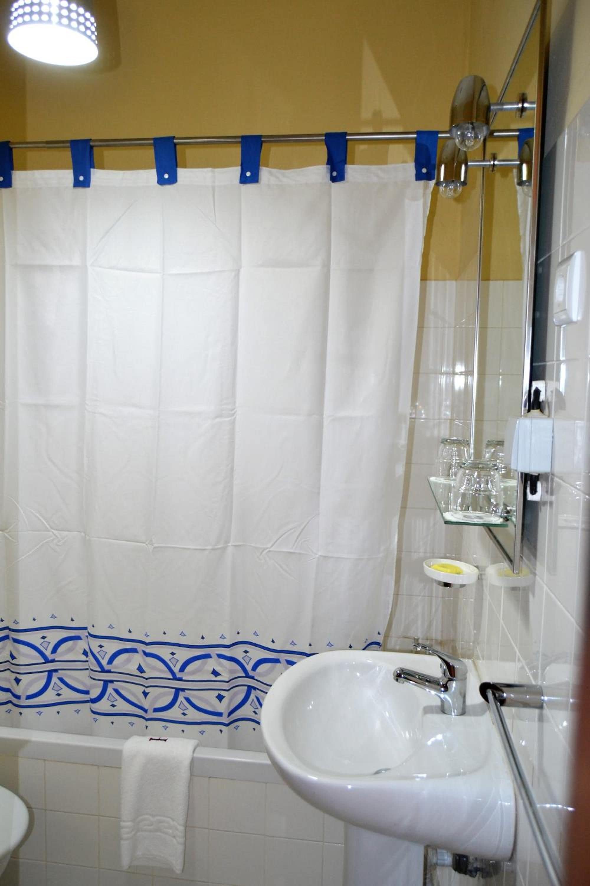 Un baño con una bañera, un lavabo blanco y un espejo.