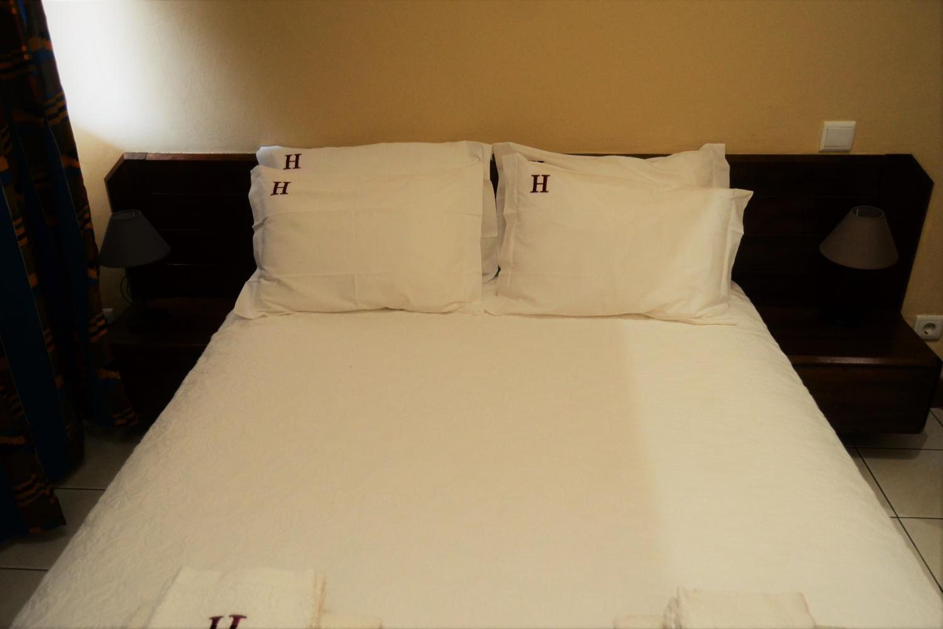 A standard hotel room with a bed, two bedside tables, and a lamp on each table.