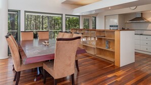 Une cuisine moderne dotée d’un îlot central, de planchers en bois et de grandes fenêtres offrant une vue sur l’extérieur.