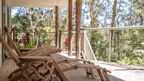 Une terrasse en bois dotée d’une rambarde, donnant sur un jardin avec des arbres et des plantes.
