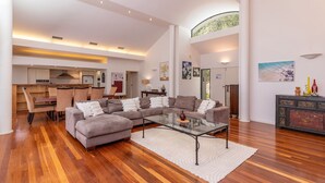 Un salon spacieux avec un grand canapé d’angle, une table basse en verre et un plancher en bois franc.