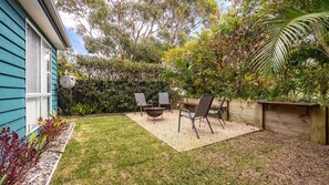 A backyard with a patio area, a fire pit, and outdoor seating.