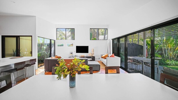 Un salon moderne avec une grande table blanche, des canapés gris et un téléviseur.