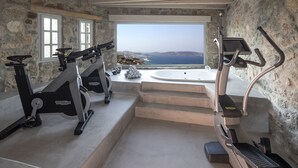 Un gimnasio en casa con equipo de ejercicio y vista al mar.