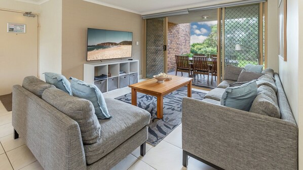 A living room with a sofa set, a coffee table, and a TV mounted on the wall.