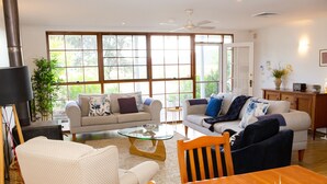 A spacious living room with two sofas, a dining table, and a coffee table. - Large villa on private vineyard in prime and secluded location (Pokolbin)