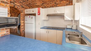 A compact kitchen with white cabinets, a stainless steel sink, a built-in oven, and a microwave.
