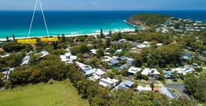 An aerial view of a coastal residential area with houses, a beach, and a clear view of the ocean.