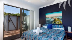 A bedroom with a bed, a painting, and a sliding glass door leading to an outdoor area. - Aqua Apartment #4 - Pacific Palms Holidays (Blueys Beach)