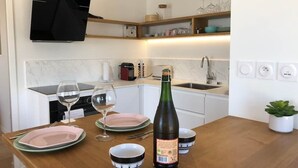 Een moderne keuken met een houten aanrecht, wijnglazen, een fles wijn en een kleine plant in een pot.