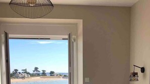 Een slaapkamer met een groot bed, uitzicht op het strand en een balkon.