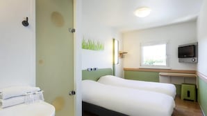 Quarto de hotel com cama, mesa de cabeceira, televisão e janela.