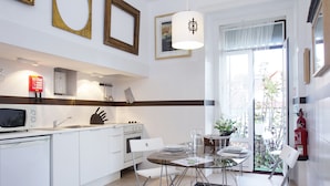 Uma cozinha moderna com armários brancos, uma mesa de jantar com cadeiras e uma grande janela com vista para o exterior.