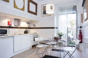 Een moderne keuken met witte kastjes, een eettafel met stoelen en een groot raam met uitzicht.