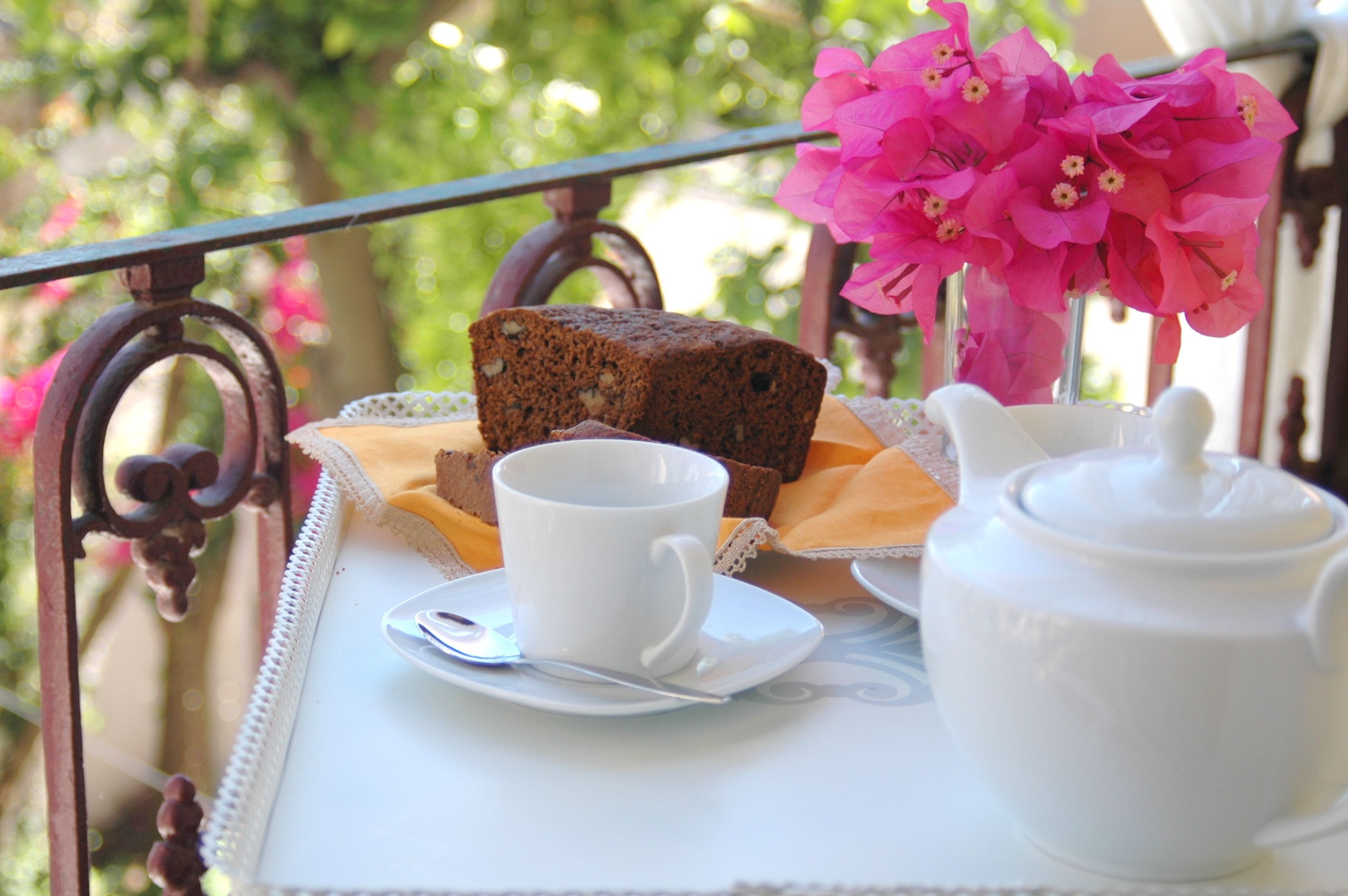 A tray with a loaf of bread, a cup, and a teapot on a table with a lace doily.