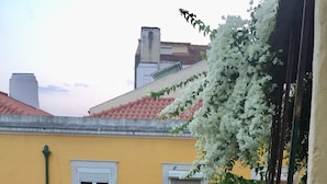Um edifício amarelo com telhado de telhas vermelhas, flores brancas e toalha de mesa branca.