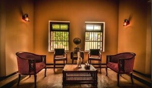 Traditional-style chairs flank a central table, adorned with a decorative vase and sculpture, in a warm, inviting room.