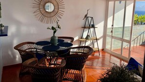 Une pièce meublée de mobilier en osier, avec un miroir et une vue sur l’océan.