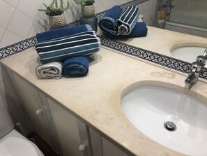 Un baño con un lavamanos, un espejo y toallas apiladas en la encimera.