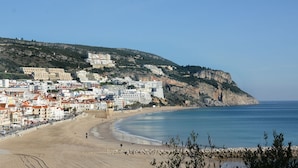 Une ville côtière dotée d’une plage de sable, de bâtiments le long de la côte et d’une falaise en arrière-plan.