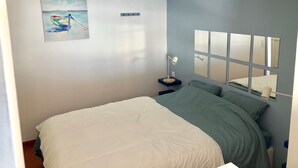 Une chambre à coucher avec un lit, une table de chevet, une lampe, un tableau et un miroir au mur.