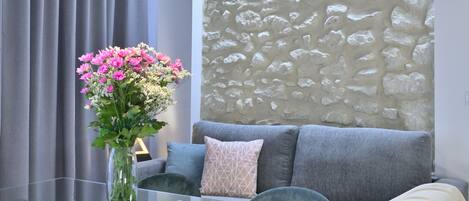 A modern living room with a glass table, a sofa, and a decorative wall.
