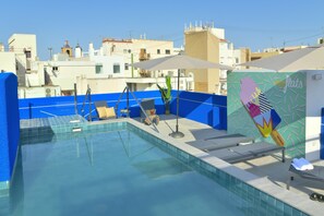 A rooftop pool with clear blue water, a blue tiled deck, and a mural on the wall. - MyFlats Luxury Downtown (Alicante)