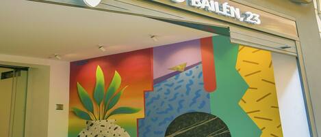 A colorful storefront with the name 'Ballen 23' and a vibrant mural with geometric shapes and a pineapple.