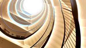 Een spiraaltrap met een modern ontwerp, bestaande uit een reeks opwaartse treden en een centrale lichtbron.