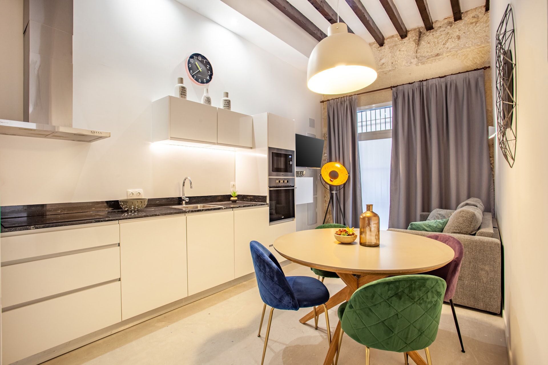 Une cuisine moderne avec une table de salle à manger ronde, deux chaises et un four encastré.