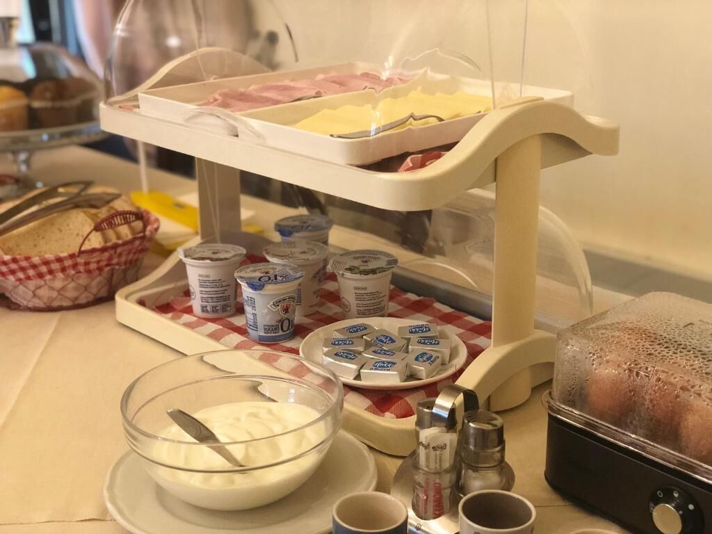 Montaje de bufé con diversos alimentos, incluyendo un tazón de yogur, salsas y una bandeja de embutidos.
