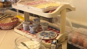 A buffet setup with a variety of food items, including a bowl of yogurt, condiments, and a tray of sliced meats.