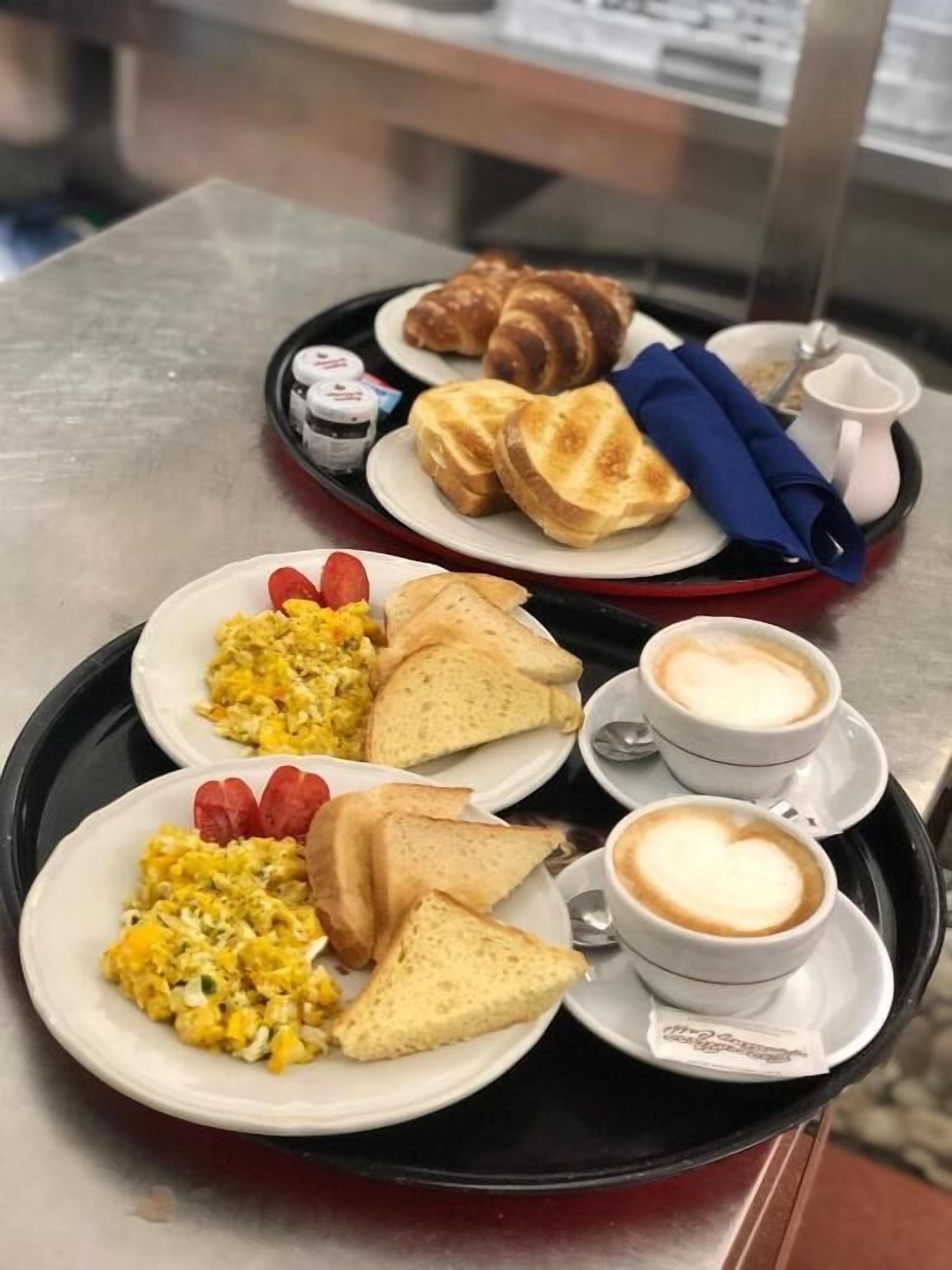 Ein Tablett mit Frühstücksleckereien, darunter Rührei, Toast, Erdbeeren und kaffeeherz.