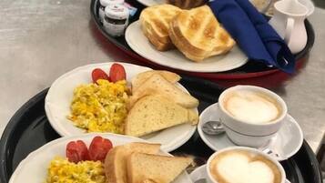Ein Tablett mit Frühstücksleckereien, darunter Rührei, Toast, Erdbeeren und kaffeeherz.