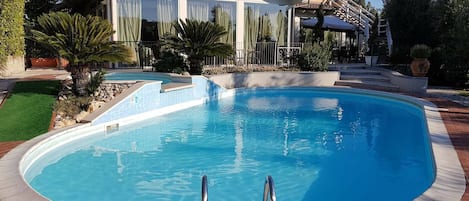 Una piscina al aire libre de temporada, sombrillas