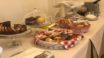A buffet table with various baked goods, including bread, pastries, and muffins.