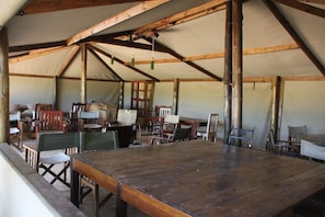 A large wooden table with chairs in a tent-like structure. - Miombo Safari Camp (Dete)