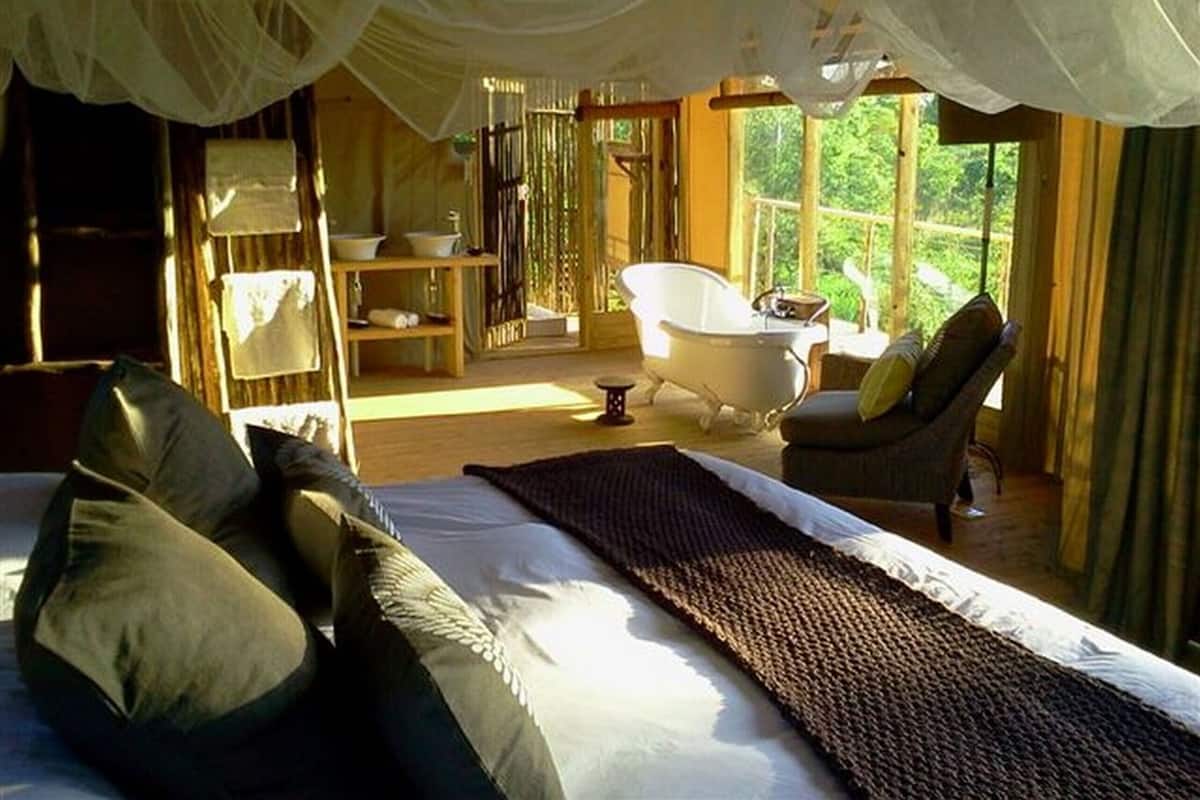 A bedroom with a large bed, a bathtub, and a chair.