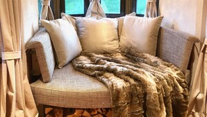 A cozy room with a sofa bed, a hanging light fixture, and a view of the outdoors through a window with curtains. - Bauernhaus-Schloss Wagrain (Ebbs)