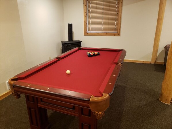 Een pooltafel met een rode viltkleed en een witte bowlingbal, gelegen op een bekleed vloerkleed.