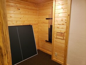 A corner room with wooden walls, a black cabinet, and a wooden cabinet with a shelf. - Beautiful Yellowstone Cabin - Hot Tub - Game Room (Island Park)