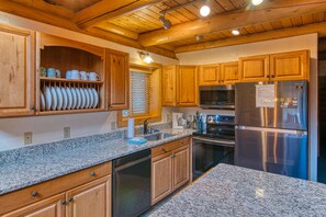 A kitchen with wooden cabinets, granite countertops, stainless steel appliances, and a built-in oven.