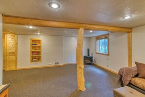 Une pièce spacieuse avec un plafond orné de poutres en bois, une bibliothèque intégrée, une cheminée et une fenêtre.
